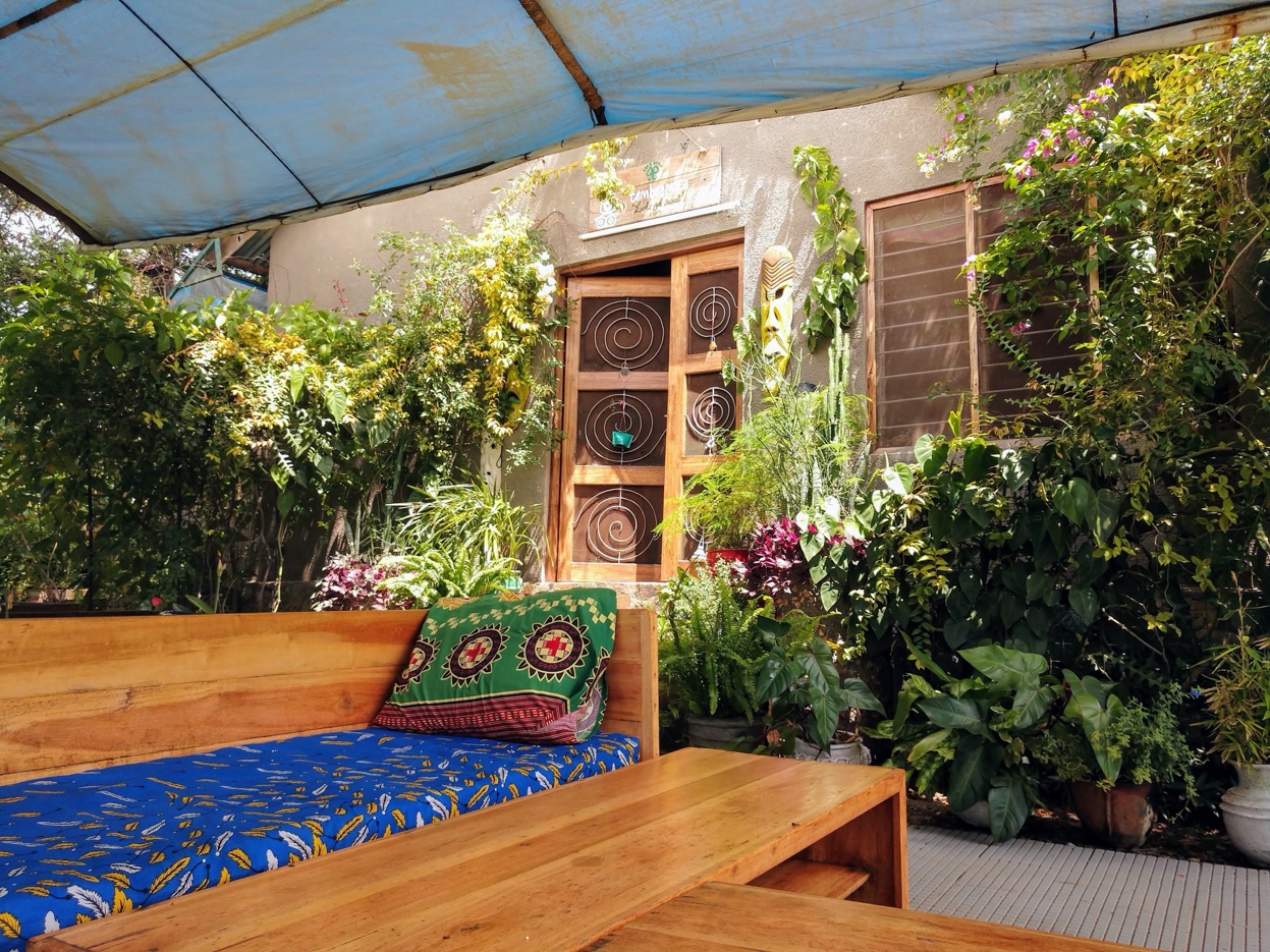 Outdoor lounge area with handcrafted wooden bench and kitenge cushions