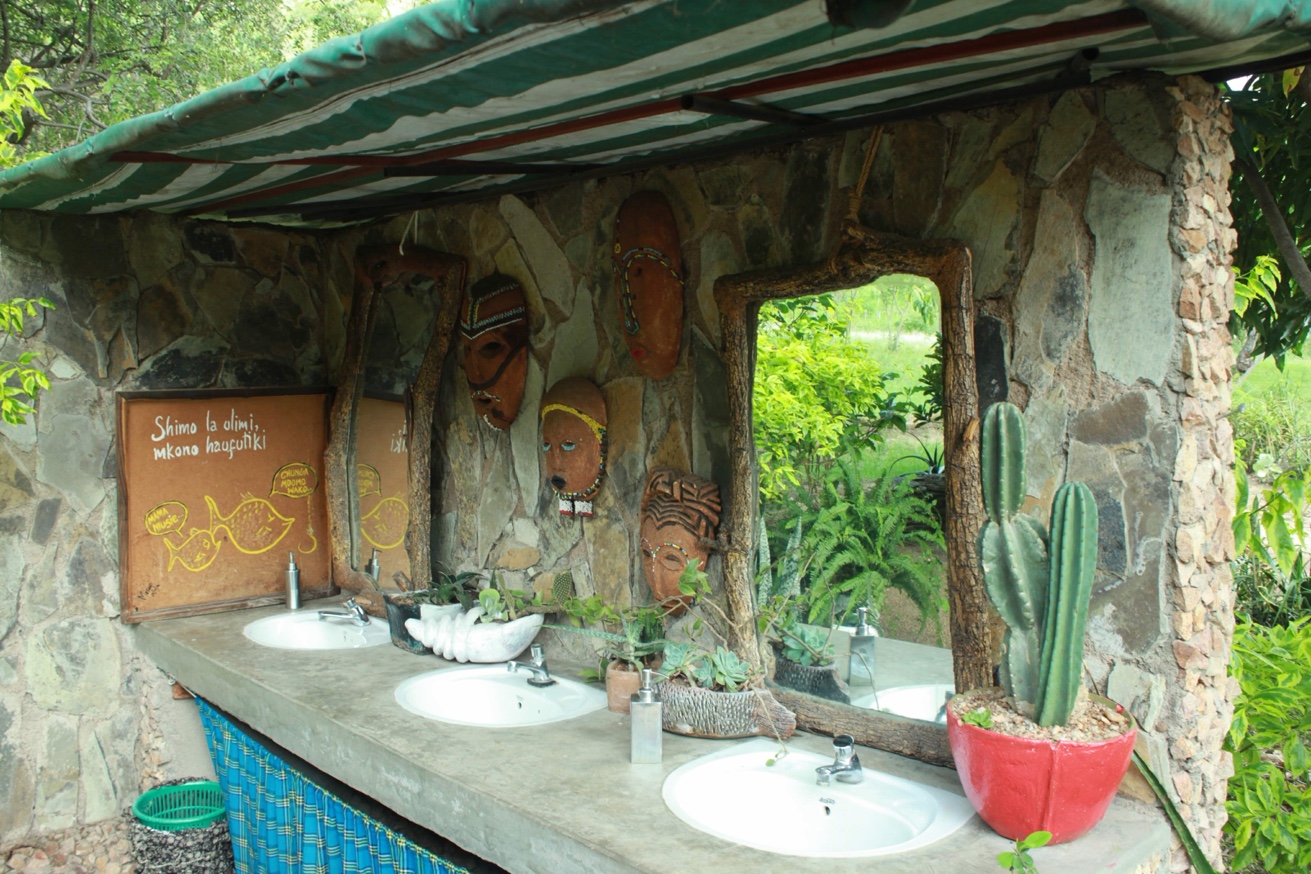 Open-air stone washstation with traditional African masks
